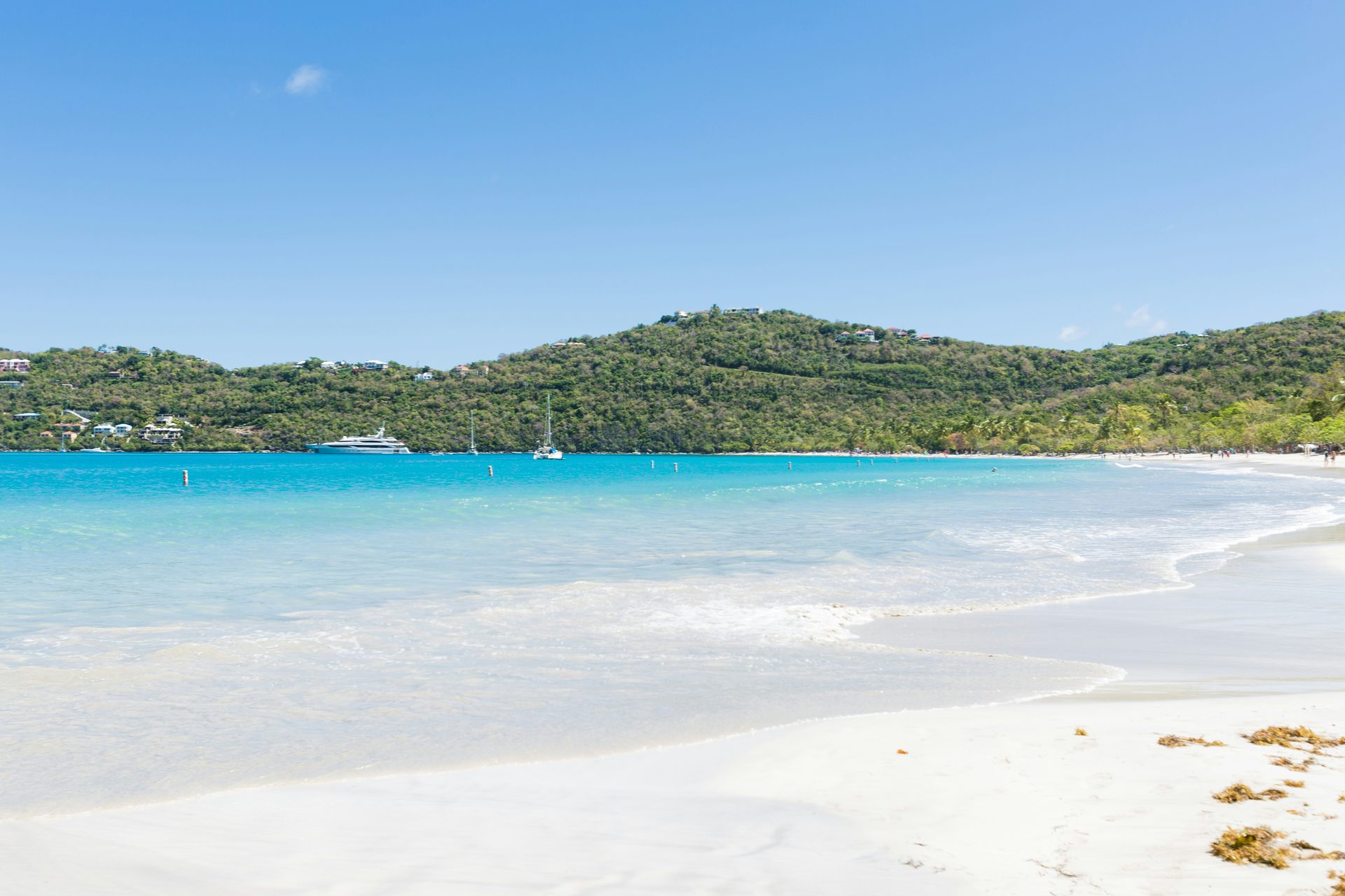Magens Bay on St Thomas, US Virgin Islands: surf running up white sand, yachts at anchor in turquoise water below green hills